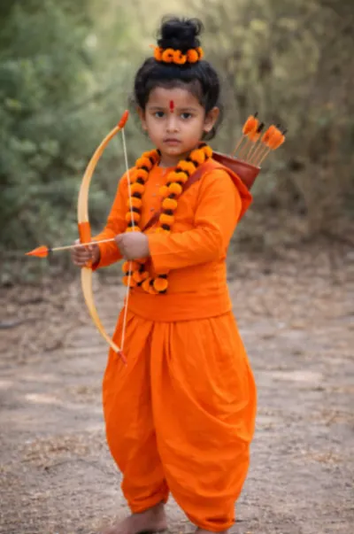 Child wearing a saffron Vanvasi Ram fancy dress with kurta, dhoti, orange garlands, bow and quiver