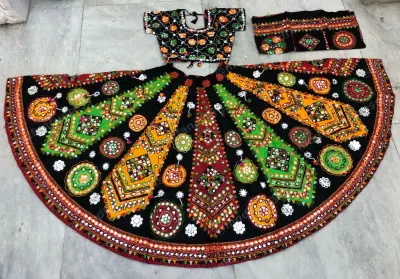Black garba lehenga laid flat — multicolour kite panels and circular mirror roundels on black with an embroidered black choli
