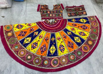 Magenta dandiya lehenga laid flat — yellow, orange, blue and green diamond panels with mirror medallions and a magenta border