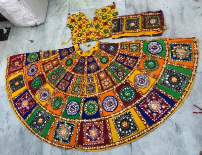 Multicolour patchwork garba lehenga laid flat — square mirror-work panels in red, green, blue and orange with a yellow mirrored choli