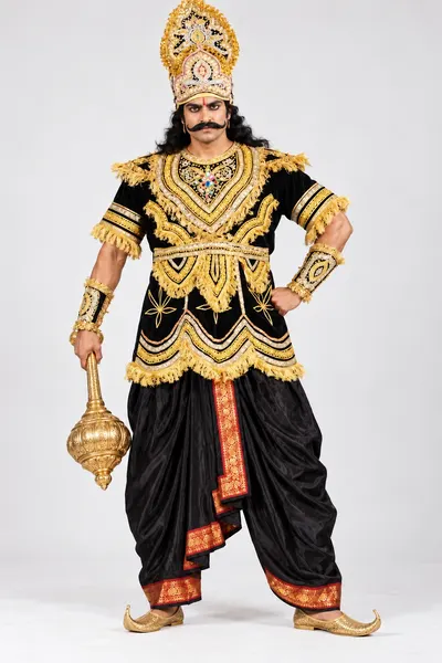 Man wearing an adult Ravan costume — black velvet with gold zari, red-bordered dhoti, gold mukut and gada