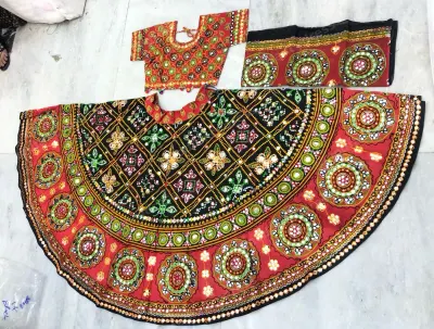 Red and black garba lehenga laid flat — black lattice yoke, circular mirror medallions on red, with matching choli and black dupatta