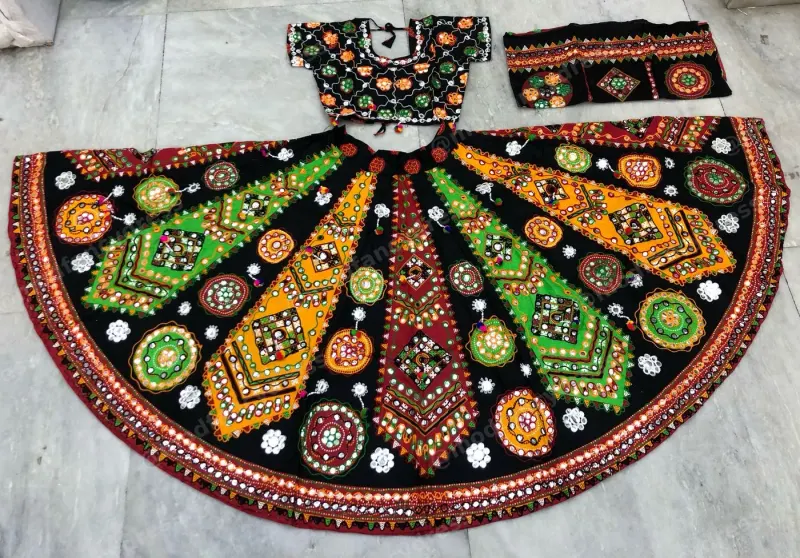 Black garba lehenga laid flat — multicolour kite panels and circular mirror roundels on black with an embroidered black choli