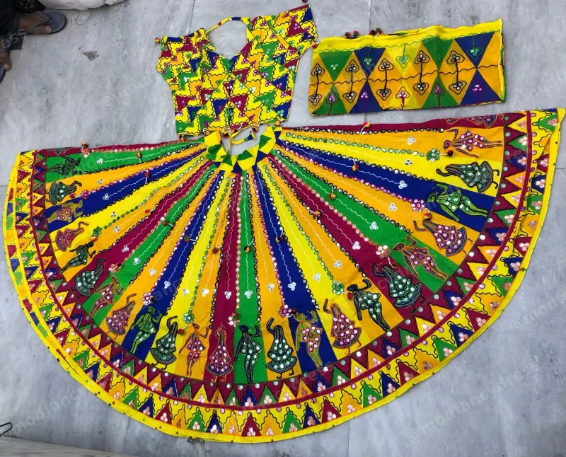 Printed garba chaniya choli laid flat — yellow, green and blue stripes with garba dancer and peacock motifs and a zigzag border