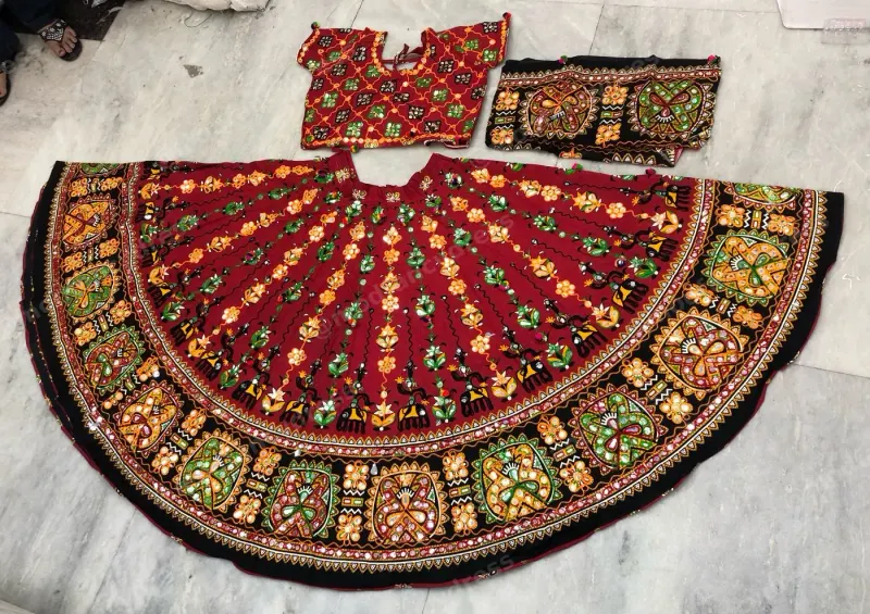 Maroon dandiya lehenga laid flat — Kutchi floral embroidery with black border, matching embroidered choli and dupatta