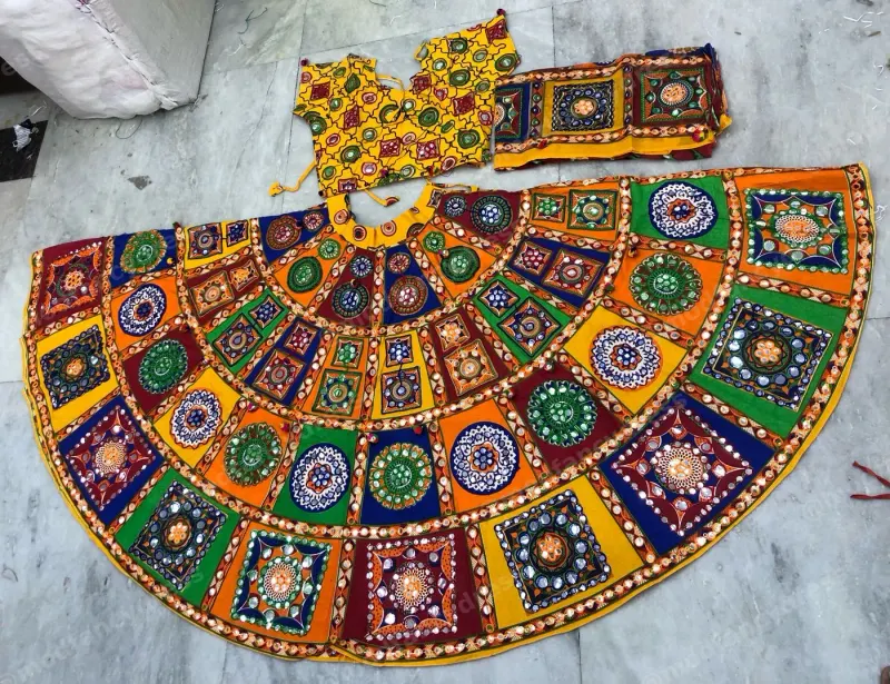 Multicolour patchwork garba lehenga laid flat — square mirror-work panels in red, green, blue and orange with a yellow mirrored choli
