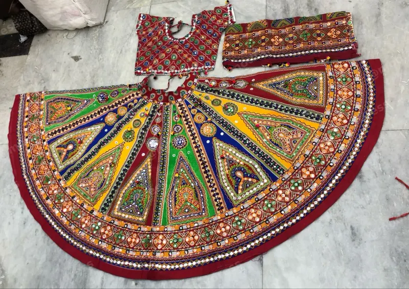 Multicolour garba chaniya choli laid flat — triangular mirror-work panels in green, blue, yellow and red with a maroon border